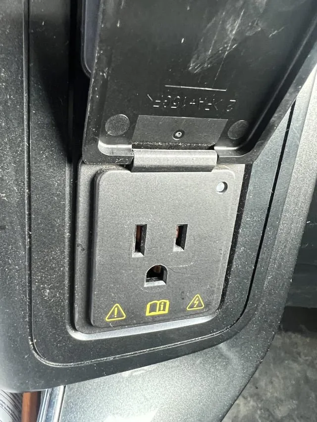 Portable electronics charging inside a truck near the 120-volt power outlet.