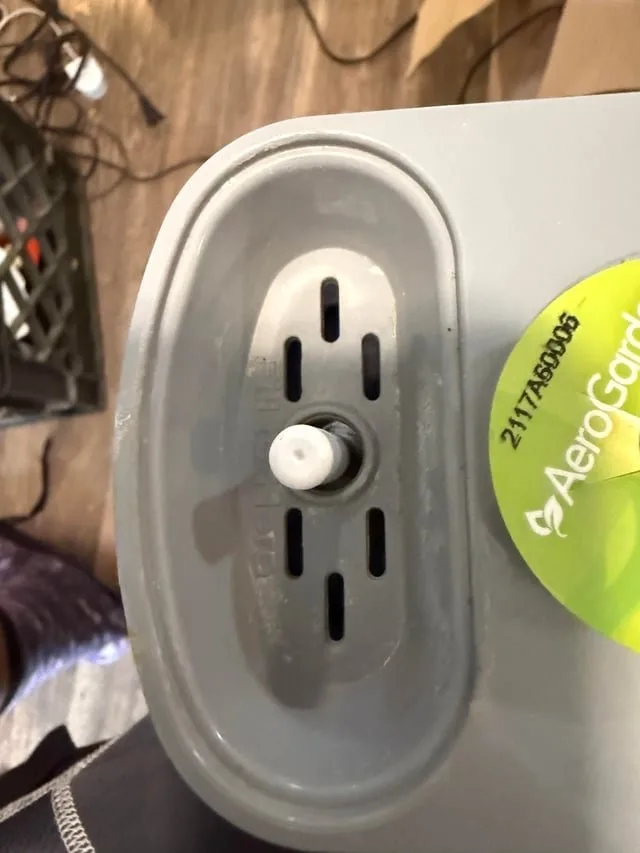 Checking the power cord connection at the base of a hydroponic indoor garden.