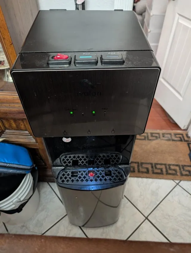 A water dispenser positioned too close to a wall, blocking necessary air circulation.