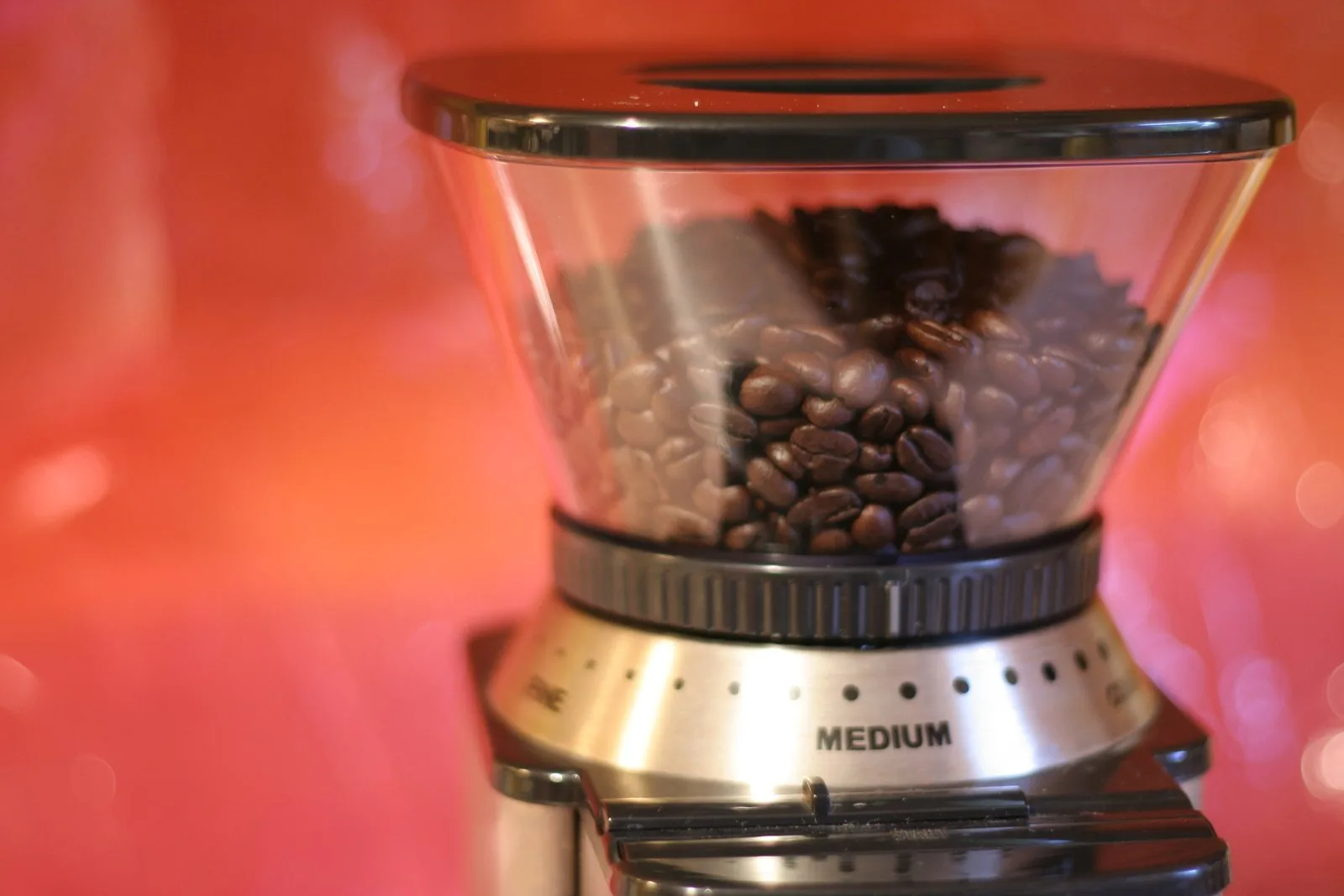 Hand pressing the reset button on the bottom of a coffee grinder.