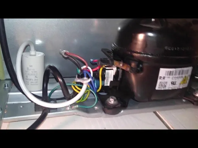 A mini fridge interior with frost buildup and a towel for defrosting.