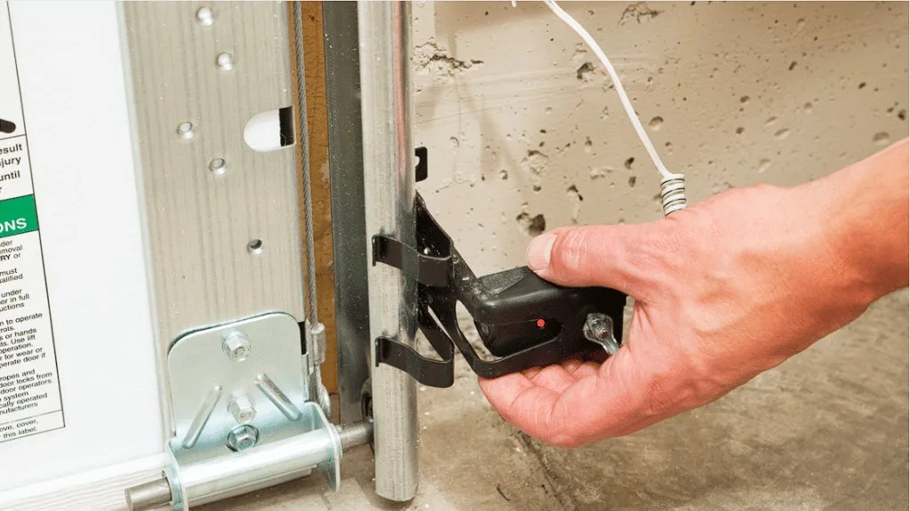A person holding a remote control while troubleshooting a garage door system.