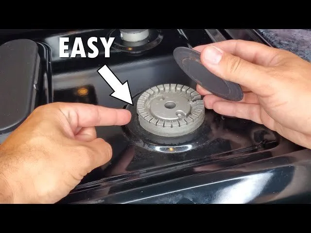 A person realigning a misaligned burner cap on a gas stove for better ignition.
