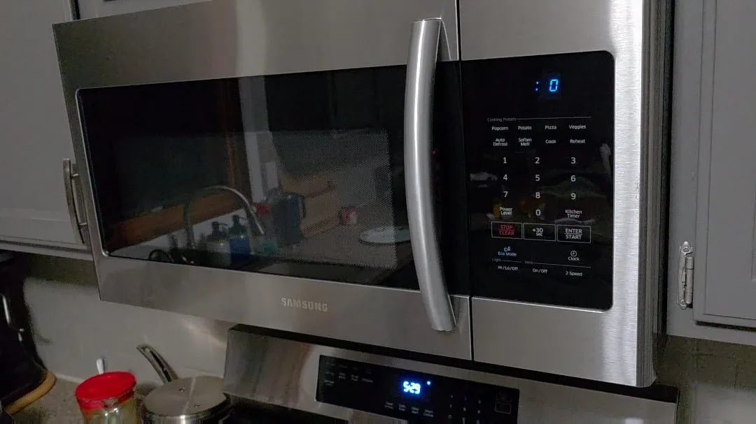 A notepad and pen sitting on a kitchen counter next to a microwave.