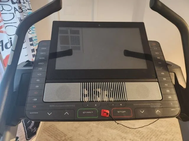 A straightened metal paperclip and a SIM card tool placed near a treadmill power cord.