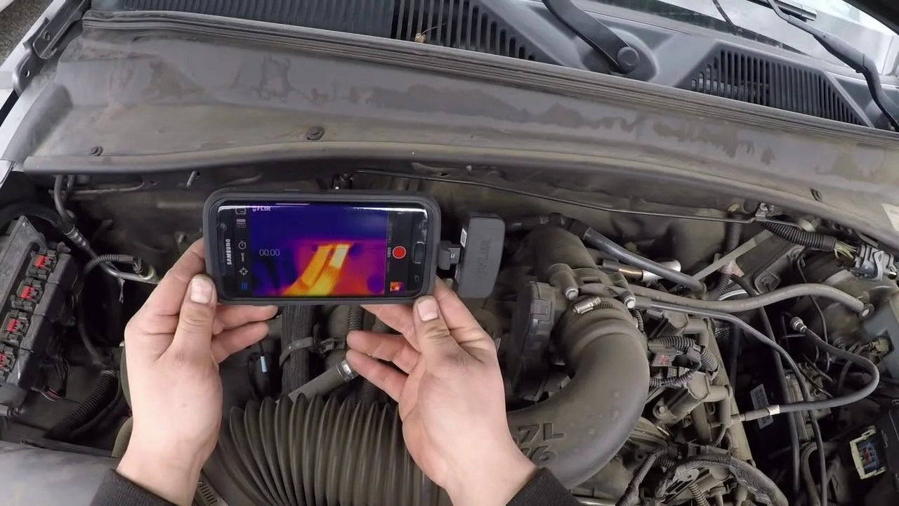 Testing the temperature of heater hoses in a Jeep Liberty engine bay.