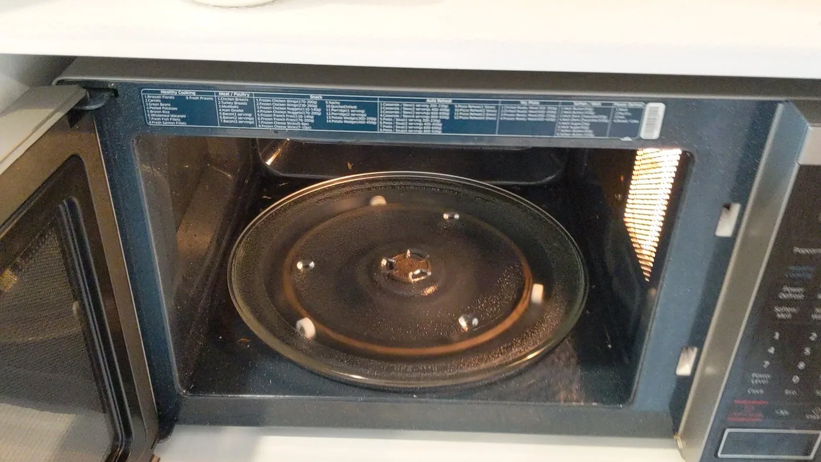 A cracked plastic drive coupler inside a microwave showing mechanical damage.