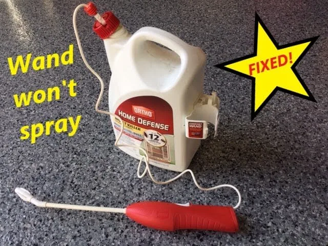A person cleaning the nozzle tip of a handheld home sprayer.