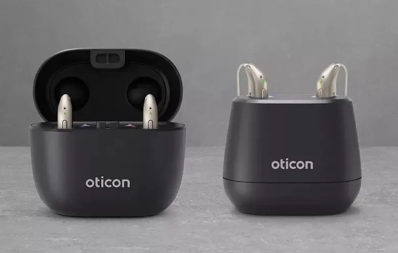 A hearing aid charger and manuals arranged neatly on a desk.