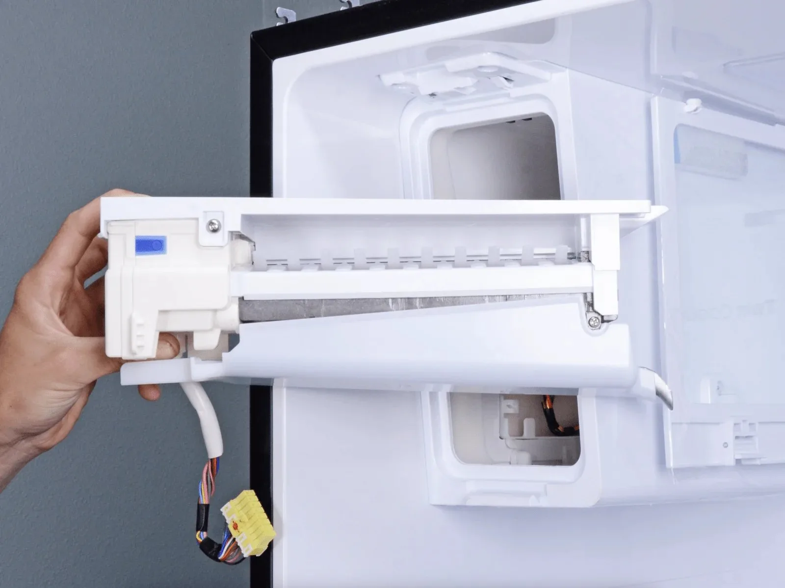 A frozen water fill tube in a refrigerator is blocked by solid ice.