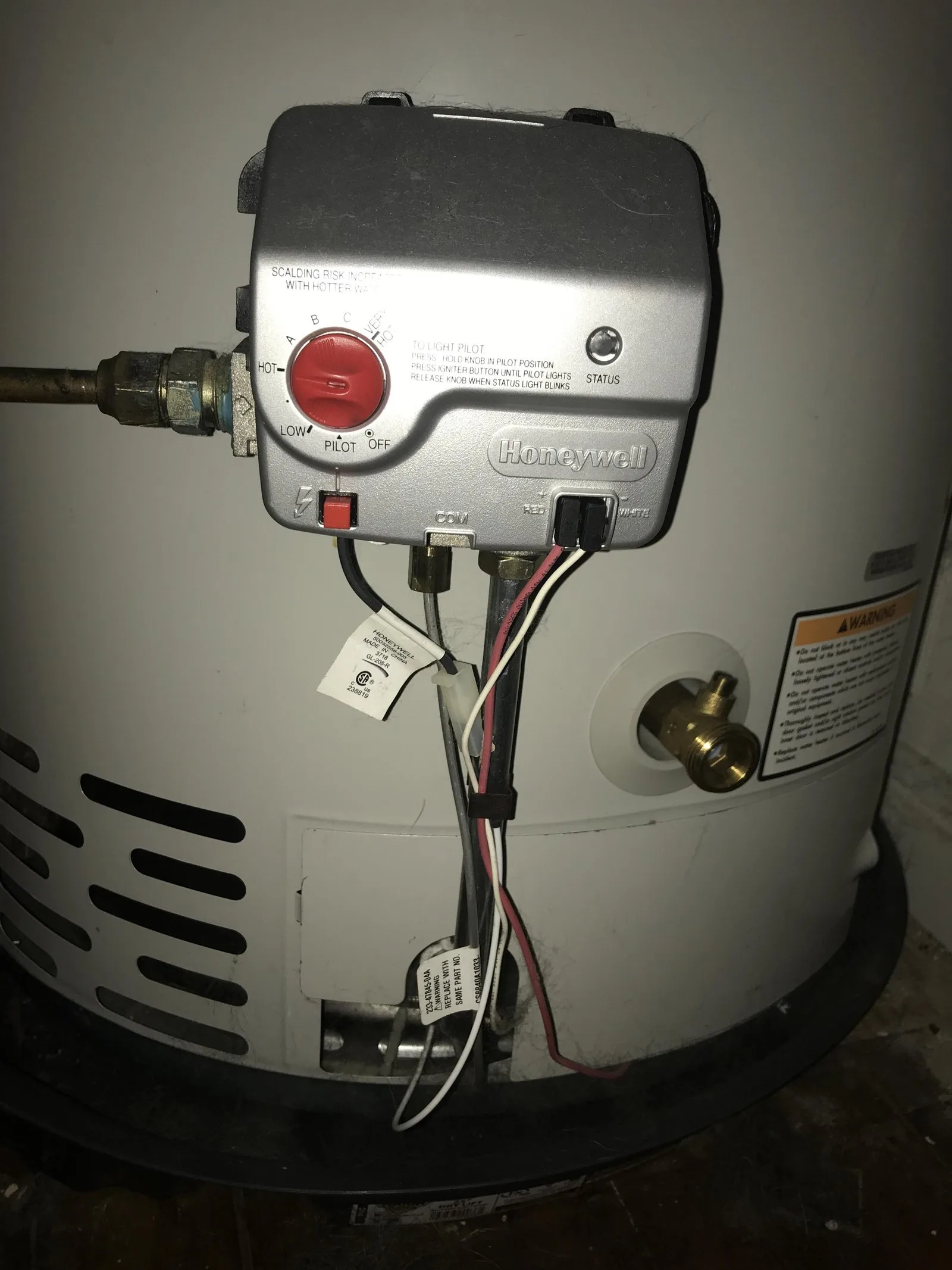 A homeowner inspects the moisture sensor located at the base of a water heater.